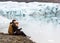 Two tourists are sitting near the glacier iceberg in Iceland