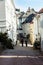 Two tourists stroll along a  street with white houses