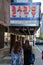 Two tourists take a picture of the sign for the famous Radio City Music Hall theater, the home of the Rockettes, located in