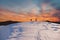 Two tourists walk on a mountain slope to the summit against the backdrop of mystical clouds at sunset