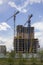 Two tower cranes near a modern high-rise building under construction