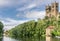 Two towers sticking up through a forest and a boat house and bridge