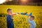 Two toys airplanes in hands boys looking at each other in yellow field on summer day