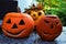 Two traditional carved halloween jack o lanterns in front and one non carved in back, placed on forefront on stone tiled floor