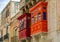 Two traditional Maltese enclosed wooden balconies painted in red and orange