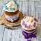 Two traditionally baked orthodox paskas with glace icing and bright blue and violet flowers on white woooden background