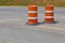 Two traffic safety barrels on an asphalt street, road construction barriers