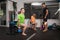 Two trainees woman and man doing some lunges with weight