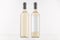 Two transparent wine bottles with blank white label and without label, on white wooden board, mock up.