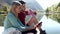 Two travel hikers using mobile phone and drinking water while sitting in front of the lake in mountain.