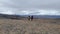 Two travelers with large backpacks and trekking poles walk through the tundra fields of Kamchatka.