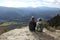 Two trekkers resting contemplating on the top of a cliff