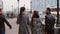 Two trendy girls and two stylish men cheerfully walk in the city and talk. Slow mo, steadicam shot, back view