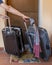 Two trolley suitcases are dragged by hands away from the closed wooden door of a house