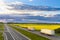 Two trucks on highway going through yelow fields