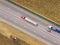 Two trucks on the higthway. cargo delivery driving on asphalt road along the agriculture fields. seen from the air