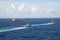 Two Tugs and Orange Tanker on Blue Sea