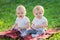 Two twin girls play with colored toys on a blanket