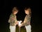 Two twin girls play with a street lamp