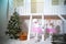 Two twin sisters in doggie dresses at the front of a white wooden house are playing. Girls and poodles decorated for Christmas and