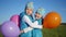 Two twin sisters hugging and kissing. Children hold balloons