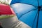Two umbrellas, one red and one blue being used on a wet tree lined street. Shallow focus