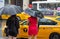 Two undefined elegant dressed women hailing a taxi cab under heavy rain in New-York