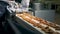 Two uneven rows of biscuits are moving along the conveyor belt in a factory facility