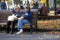 Two unidentified happy retired women rest on a bench, autumn scene