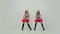 Two uniformed cheerleaders with red pompoms dance an uplifting dance, move their hips. Girls dance synchronously on a