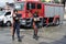 Two uniformed lady fire fighters walking By parked fire truck