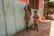 Two unknown small boys, standing next to wall, smiling and waving to tourist visiting local slum. Many children suffer under poor