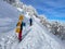 Two unrecognizable active tourists snowshoe up a scenic hiking trail in Alps.