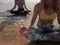 Two unrecognizable girl practice meditation sitting in lotus pose at sandy shore