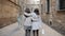 Two unrecognizable girls friends walk hugging along a historic street