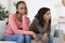 Two upset african women sitting on sofa, had quarrel