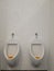 two urinals next to white tiled wall