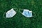 Two used sanitary masks lying on grass ground. Disposable recyclable face mask flat lay. Coronavirus, medicine, seasonal allergy