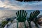 Two vacant green chairs await visitors to relax and enjoy sunset from rocky point in Caribbean