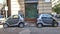 Two very small identical gray cars are parked in the same parking space in the city