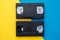 Two video tapes on yellow and blue background. Top view. VHS videotapes. Minimalistic retro concept. Copy, empty space for text