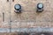 Two vintage air conditioning units on side of old brick wall