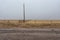 Two vintage barbwire fences meeting at a telephone pole in New Mexico on cloudy day