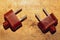 Two vintage brown power plugs without cord on the wooden background