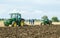 Two vintage John Deere tractor pulling a plough