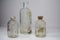 Two vintage vaccine bottles and one medical beaker, aged and patina on a white background