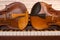 Two violins lying on a piano keyboard