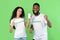 Two Volunteers Showing Phone Screen Gesturing Yes On Green Background