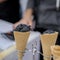 Two waffle cones, horns with balls of trendy black ice cream and hand of the seller. Delicious cooling portion for fun