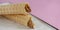 Two waffle cones with sweet boiled condensed milk in white plate on pastel pink background. Condensed tubules.